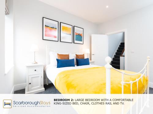 Dormitorio blanco con cama con sábanas amarillas y almohadas azules en Scarborough Stays - Trafalgar Lodge - 4 bedroomed house - Free Parking, en Scarborough