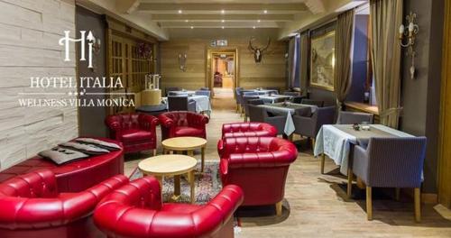 a restaurant with red leather furniture and tables and chairs at Hotel Italia in Castello di Fiemme