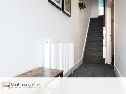 a hallway with a staircase with a wooden table at Scarborough Stays - Trafalgar Lodge - 4 bedroomed house - Free Parking in Scarborough