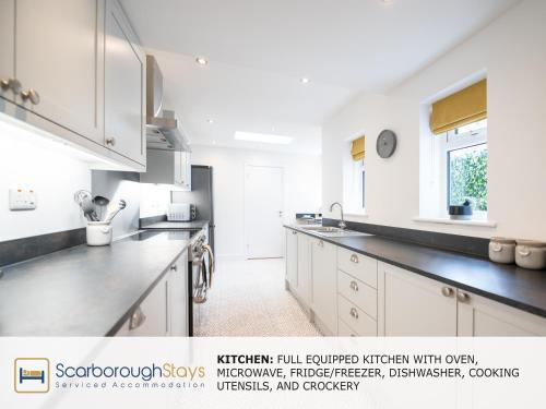a kitchen with white cabinets and black counter tops at Scarborough Stays - Trafalgar Lodge - 4 bedroomed house - Free Parking in Scarborough