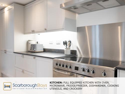 a kitchen with white cabinets and a stove at Scarborough Stays - Trafalgar Lodge - 4 bedroomed house - Free Parking in Scarborough