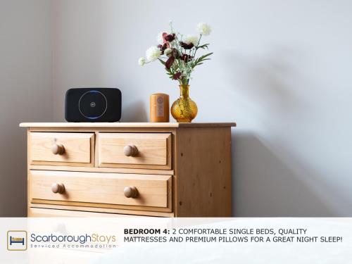 a vase of flowers sitting on top of a dresser at Scarborough Stays - Trafalgar Lodge - 4 bedroomed house - Free Parking in Scarborough