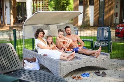 a family sitting on top of a bed at Barack Thermal & Natura Apartments in Tiszakécske