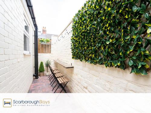 a bench next to a wall with a plant at Scarborough Stays - Trafalgar Lodge - 4 bedroomed house - Free Parking in Scarborough
