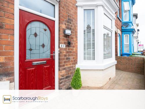 a red door on the side of a brick house at Scarborough Stays - Trafalgar Lodge - 4 bedroomed house - Free Parking in Scarborough