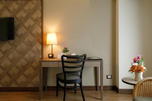 a desk with a chair and a lamp in a room at Amora Thapae Hotel Chiang Mai in Chiang Mai