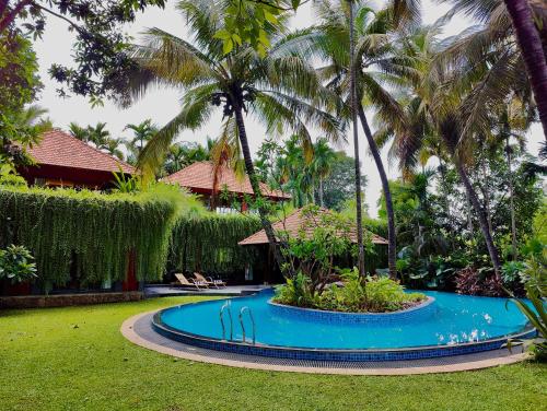 a swimming pool in front of a house with palm trees at SaffronStays Kimaya, Alibaug in Alibaug