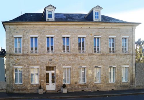 an old brick building with white doors and windows at Normand'Histoire Gite 1869 in Isigny-sur-Mer