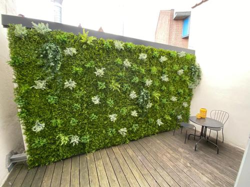a green hedge with flowers and a table and chair at Maison Bon Apartments in Den Bosch