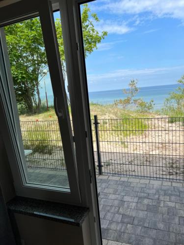 a sliding glass door with a view of the ocean at Apartamenty i Domki WyDmy Międzywodzie in Międzywodzie