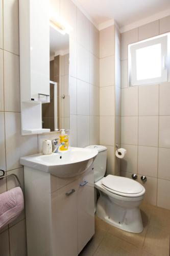 a white bathroom with a toilet and a sink at House Star in Petrovac na Moru
