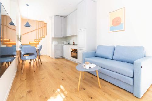 a living room with a blue couch and a table at Karklė Living Apartments, By Cohost in Karklė