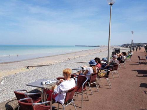 a group of people sitting at tables on the beach at Studio Les pieds dans l'eau in Dieppe