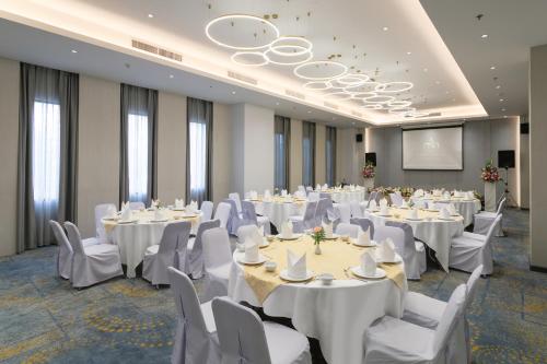 a conference room with white tables and chairs and a screen at Amora Thapae Hotel Chiang Mai in Chiang Mai
