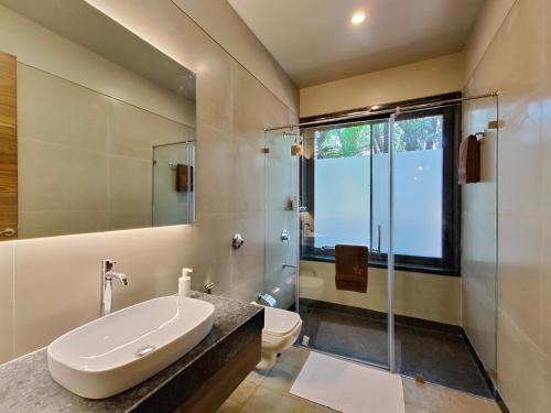 a bathroom with a sink and a shower and a toilet at SaffronStays Kimaya, Alibaug in Alibaug