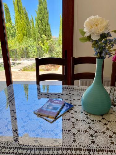 a vase sitting on a table with a book and flowers at Demelida Villa in Tsada, Paphos in Tsadha