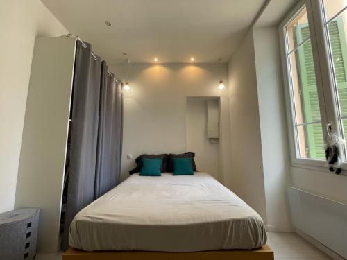 niewielka sypialnia z łóżkiem z niebieskimi poduszkami w obiekcie Nice Renting - Moneghetti Monaco - Spacious Apartment Full Equipped w mieście Beausoleil