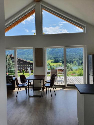 a room with a table and chairs and large windows at Ferienhäuser Seetraum Premium Card inklusive in Weissensee