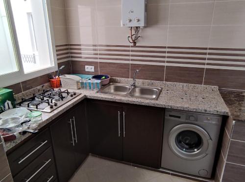 a kitchen with a sink and a washing machine at Appartments Achahbar in Al Hoceïma