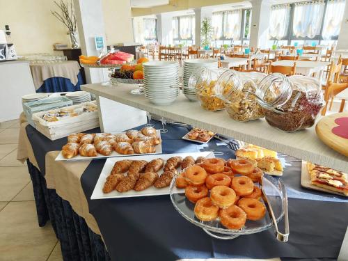 a table with plates of donuts and pastries on it at Blu Star Hotel in Gabicce Mare
