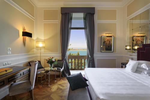 a hotel room with a bed and a desk and a window at Grand Hotel Des Etrangers in Siracusa
