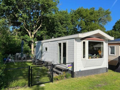 a white tiny house in a yard with a table at Vakantiepark Kijkduin - 884 in The Hague