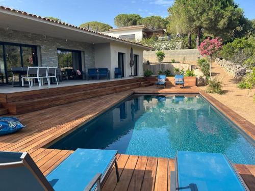 een zwembad met een houten terras en een huis bij Villa Monte e Mare, piscine chauffée, climatisée à 5 mn de la plage de santa giulia in Porto-Vecchio