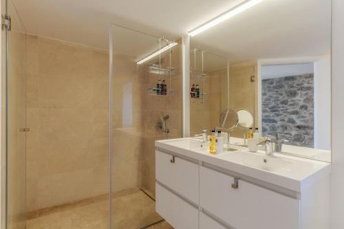 a bathroom with a sink and a glass shower at Escarpa - The Madeira Hideaway in Ponta do Sol