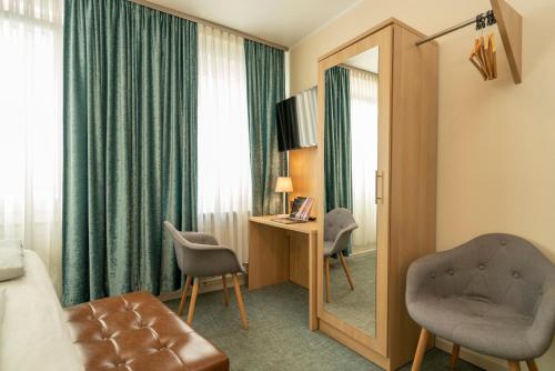 a hotel room with a mirror and a chair at NP Hotel Königshof in Dortmund