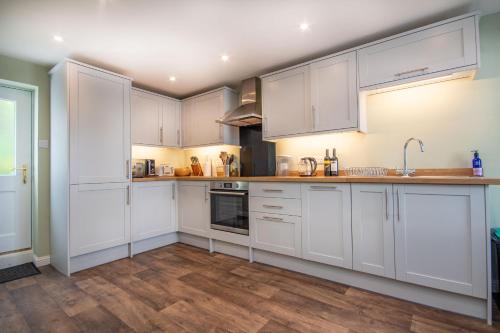 a kitchen with white cabinets and a wooden floor at Morningside in Bonar Bridge