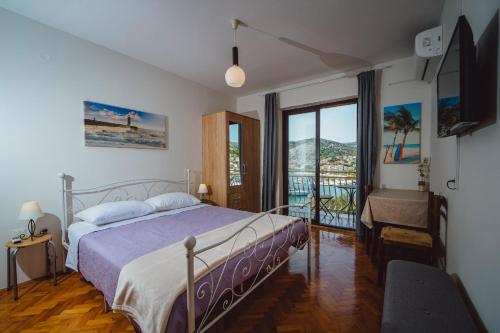 a bedroom with a bed and a balcony at Seaside Apartments in Seget Vranjica