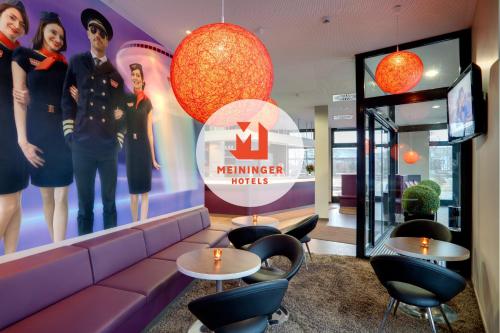 a waiting room with tables and chairs in a store at MEININGER Hotel Frankfurt Main / Airport in Frankfurt/Main