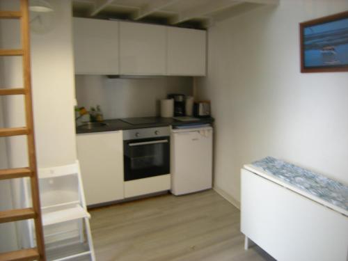 Elle comprend une petite cuisine avec des placards blancs et un réfrigérateur. dans l'établissement AV GAMBETTA, à Arcachon