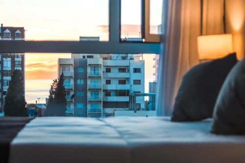a bed in a room with a view of a building at CQ MITRE in Puerto Madryn