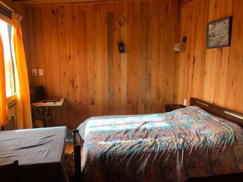 1 dormitorio con 1 cama en una pared de madera en El nirvana en Aguas Dulces