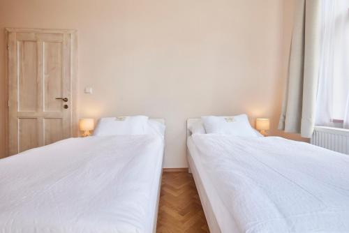 two beds in a room with white sheets at Wellness Penzion U Muzea in Liberec