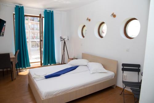 a bedroom with a bed with blue curtains and a window at Vila Nautica in Costinesti