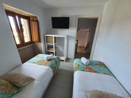 a room with two beds and a television in it at Casa Jalecha in Muxia