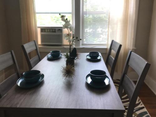 a dining room table with chairs and a wooden table with dishes at Cherry Street Vintage Apartment-Free Parking! in Tulsa