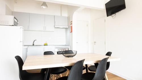 a kitchen with a wooden table and black chairs at Apartamentos Pedro for Families by Bedzy in Albufeira
