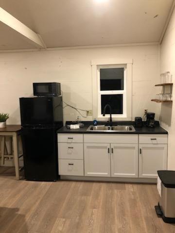 a kitchen with a black refrigerator and a sink at Avenwood Cabins in Logan