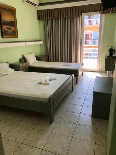 Una habitación de hotel con dos camas y una ventana. en Vila Eva, en Paralia Katerinis