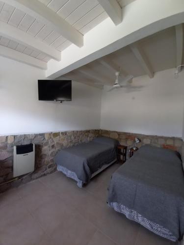 1 dormitorio con 2 camas y TV de pantalla plana en Kay Pacha en Tilcara