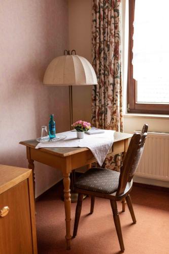 a table with a lamp and a chair with flowers on it at Gasthof Spelsberg in Altena