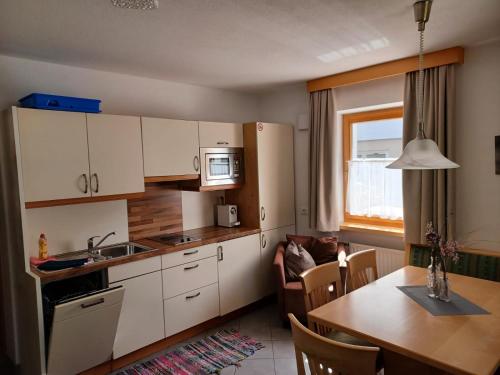 a kitchen with white cabinets and a table and a dining room at App Sonne Nr 17 in Lutago