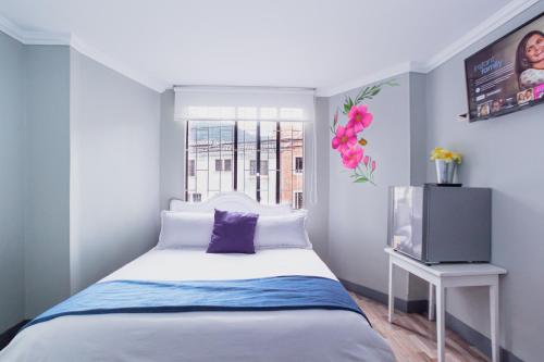 a small bedroom with a bed and a tv at ApartaSuites & Hotel Bogota Suamox in Bogotá