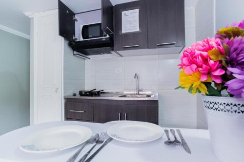 a kitchen with two plates and a vase of flowers at ApartaSuites & Hotel Bogota Suamox in Bogotá