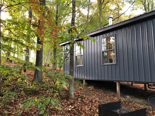 a black tiny house in the woods at Avenwood Cabins in Logan