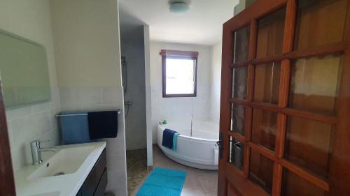 a bathroom with a tub and a sink and a door at Gîte La Besse, Claudon in Claudon