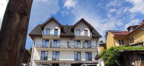 a tall white building with a black roof at Willa Kania in Szczawnica